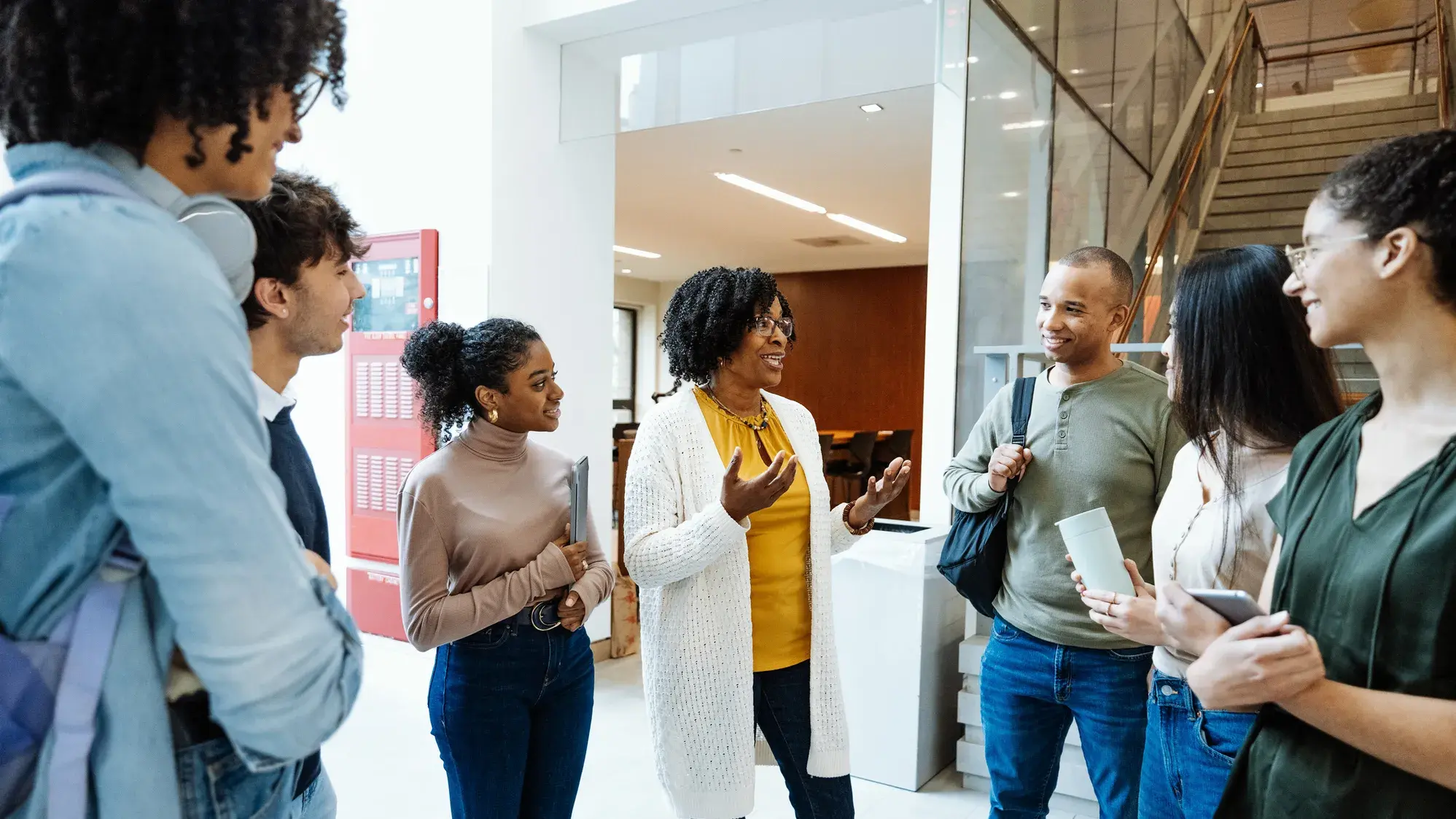 A woman leading a conversation with a group of adults in a lobby