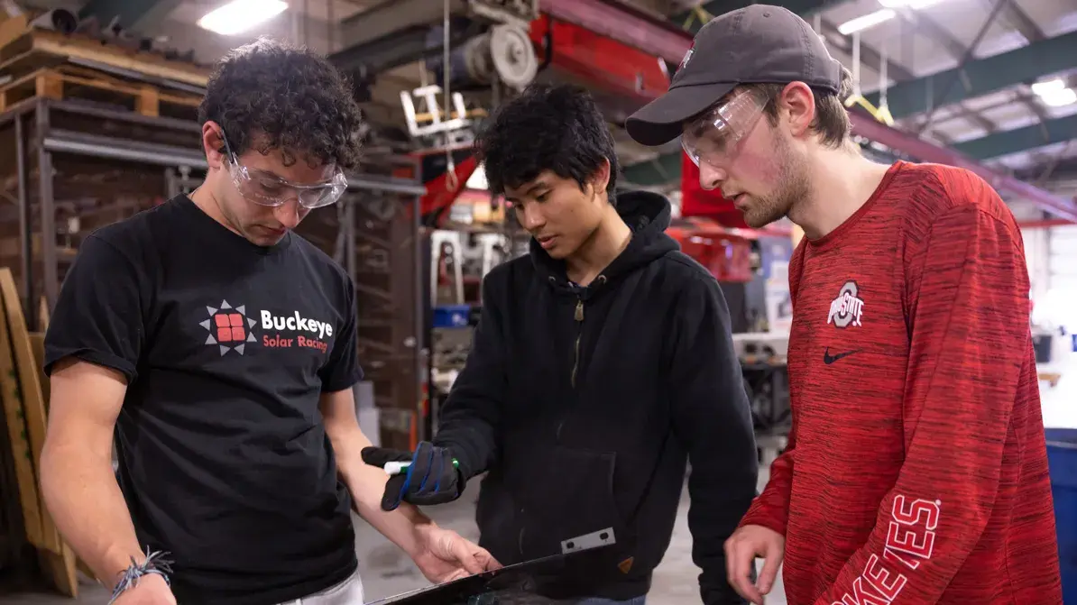 three graduate students discussing a material in a fabrication shop atmosphere