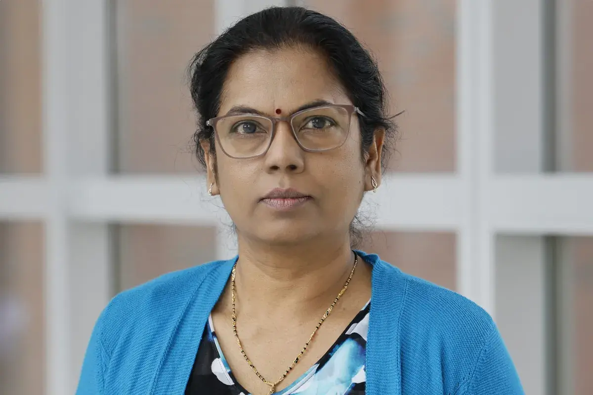 portrait of Manjula Karpurapu wearing a blue sweater and glasses