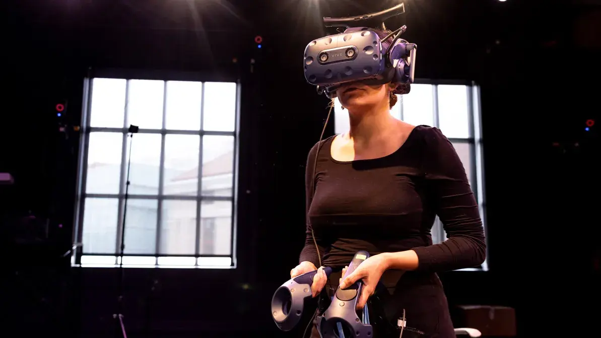 woman using an augmented reality headset and hand controls in a darkened room