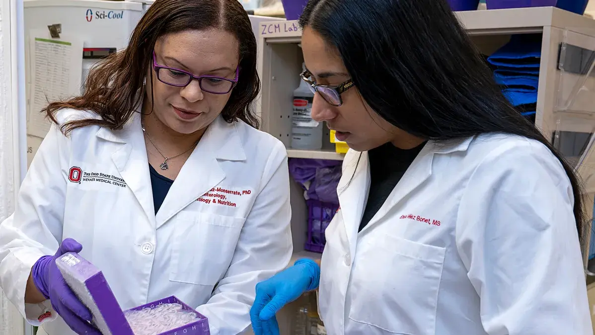 two women with lab coats on examining specimens in a cold container