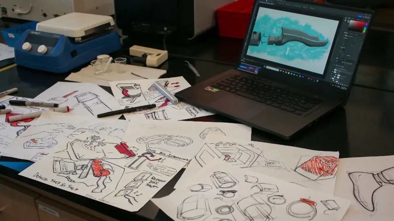 Desk with an open laptop and numerous sketches