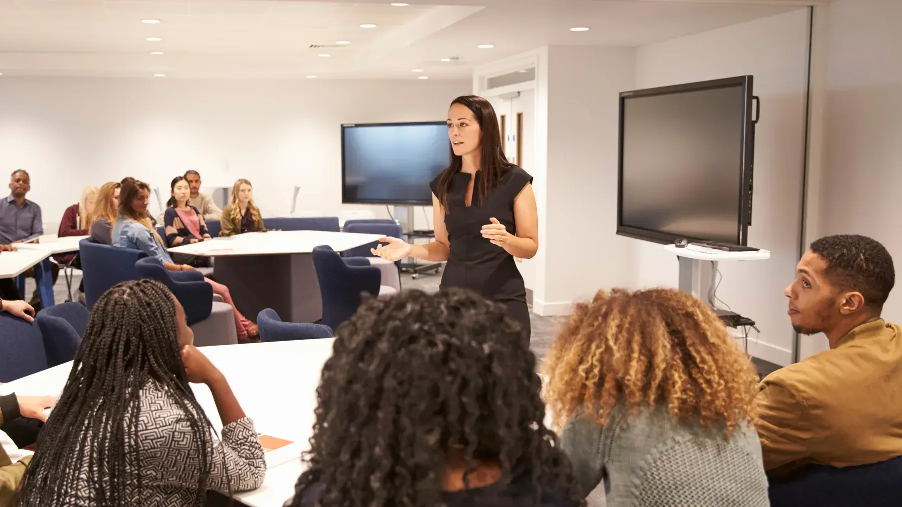 Woman leading a discussion to a group of students inside a modern classroom