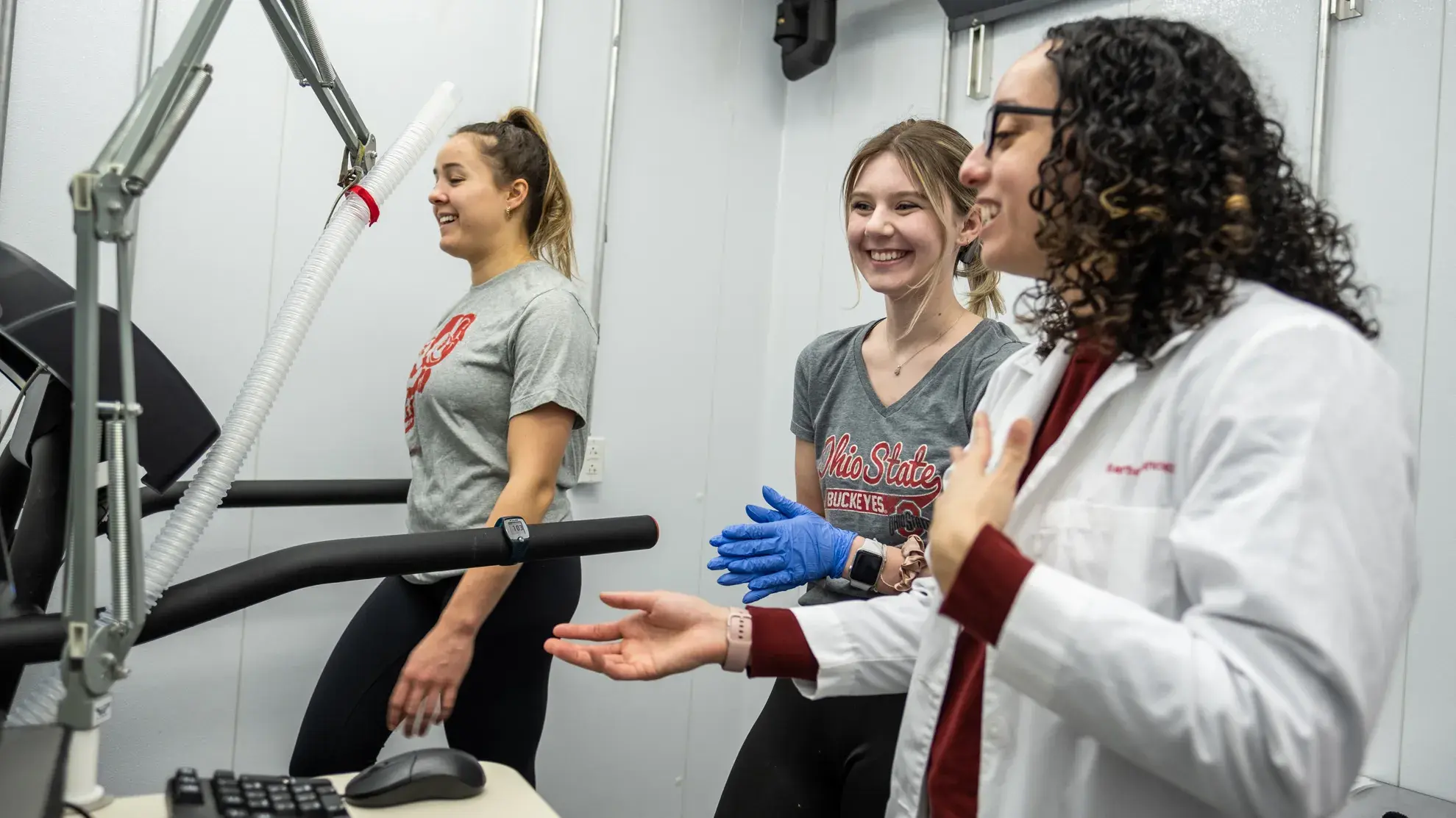 A doctor, a student and a patient. Patient is walking on a treadmill.